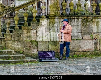 Ein Straßenmusiker spielt Saxophon für Touristen am frühen Morgen in Porto, Portugal Stockfoto