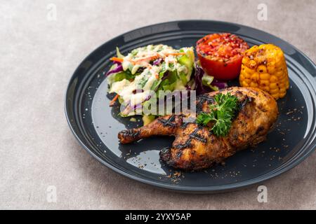 Hähnchenhälfte gebacken in einer Sauce aus Knoblauch, Soja, Ingwer und Honig. Teller mit gebackenem Mais, Salat und Tomaten. Stockfoto