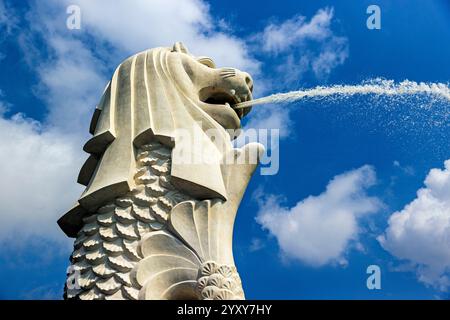 Merlion Statue im Merlion Park in Singapur sprüht Wasser vor einem klaren blauen Himmel mit flauschigen Wolken. Foto: David Rowland / One-Image.com Stockfoto