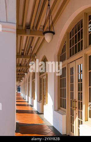 Sonnendurchfluteter Korridor mit Bögen und Hängelampen im historischen Raffles Hotel, Singapur, der zur Long Bar führt. Foto: David Rowland / One-Image.com Stockfoto