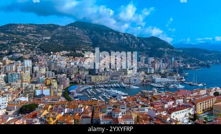 Atemberaubende Luftaufnahme von Monacos pulsierendem Hafen, luxuriösen Yachten, farbenfrohen Gebäuden und dramatischer Bergkulisse. Ideal für Reisen und Luxusleben Stockfoto