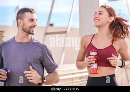 Lächelndes Fit Paar, das draußen mit Wasserflaschen joggt Stockfoto