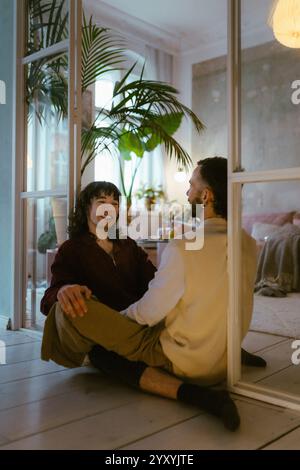 Glückliches schwules Paar, das zu Hause auf der Tür sitzt Stockfoto