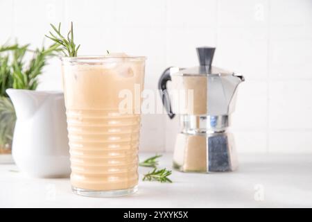 Glas aromatischer Rosmarin-Kaffee-Latte mit Eisduft, Schlagsahne oder Sahne, kaltes Kaffeegetränk mit Rosmarin-Zweig dekoriert Stockfoto