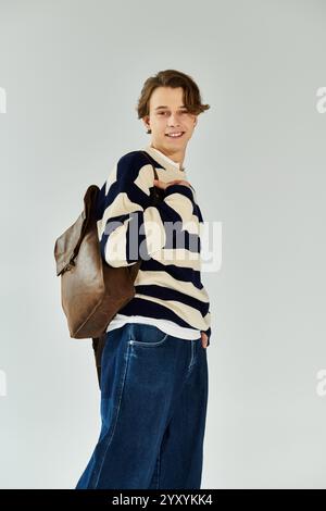 Ein hübscher junger Mann mit einem gestreiften Pullover steht selbstbewusst in einem Studio. Stockfoto