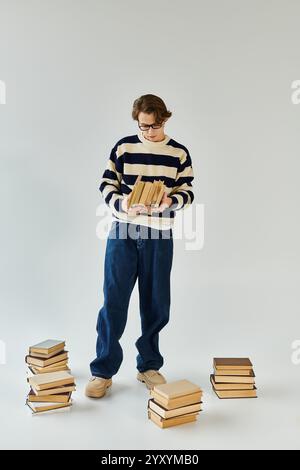 Ein junger Student in einem gestreiften Pullover studiert zwischen Büchern. Stockfoto