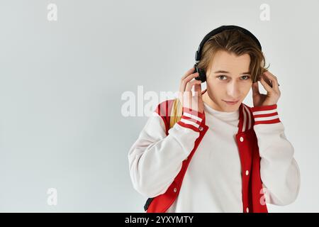 Ein gutaussehender junger Mann hört Musik, während er in einem Studio eine stylische Bomberjacke trägt. Stockfoto