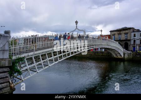 Dublin, Irland - 14. Juni 2024: Blick auf die Ha'Penny Bridge, die den Liffey überspannt und zahlreiche bewegungsunscharfe Fußgänger zeigt Stockfoto