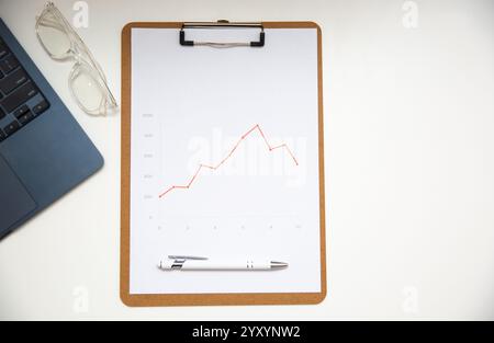 Draufsicht des Arbeitsplatztisches im Büro mit Diagrammen, Bericht über Holzablage, Brille und Stift. Stockfoto