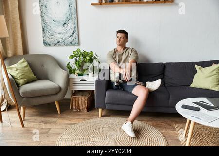 Ein junger Mann mit einer Beinprothese sitzt bequem auf einer Couch in einem stilvollen Wohnzimmer. Stockfoto