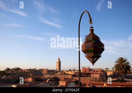 marokkanisches Design aus Glas und Metall hängt an der Skyline der Stadt mit dem Minarett der koutoubia-Moschee im Hintergrund marrakesch, marokko Stockfoto