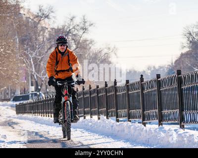Ein aufregendes Winterabenteuer in der Stadt mit dem Fahrrad. Ein Mann fährt Fahrrad auf einer verschneiten Straße Stockfoto