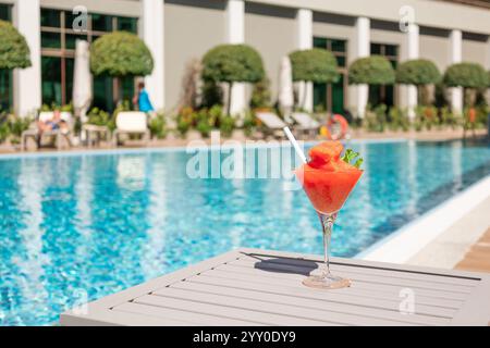 Frischer roter Cocktail mit Eis im Glas im Swimmingpool. Tropischer Saft bei Luxusurlauben. Konzept Sommerurlaub und Reisen Stockfoto