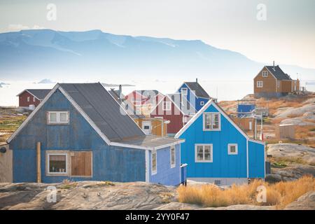 Baffin Bay, farbenfrohe typische Häuser im kleinen Dorf Uummannaq, grönländischer Eisfjord in Grönland und der Silhouetten hohe Bergrücken Stockfoto