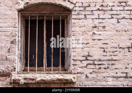 Altes vergittertes Fenster und verrottete Ziegelarbeiten Stockfoto