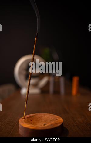 Räucherstäbchen raucht auf einem Holzständer auf dunklem Hintergrund. Aromatherapie, Rauch beim Verbrennen von Weihrauch. Rauch für Gebete und Meditation. Beten zu Stockfoto