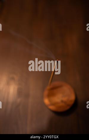 Räucherstäbchen raucht auf einem Holzständer auf dunklem Hintergrund. Aromatherapie, Rauch beim Verbrennen von Weihrauch. Rauch für Gebete und Meditation. Beten zu Stockfoto