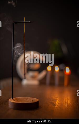 Räucherstäbchen raucht auf einem Holzständer auf dunklem Hintergrund. Aromatherapie, Rauch beim Verbrennen von Weihrauch. Rauch für Gebete und Meditation. Beten zu Stockfoto