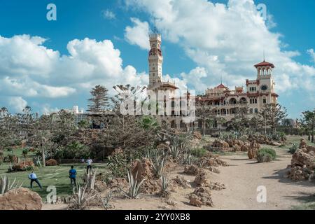 Montaza Palace in Alexandria, Ägypten, umgeben von üppigen Gärten und Wüstenfelsen, unter einem hellblauen Himmel. Historische Architektur und Landschaft. Stockfoto