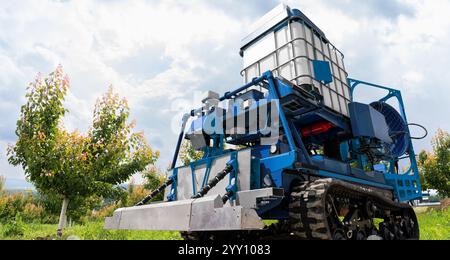 Die autonome Roboterspritze arbeitet in einem Obstgarten. Konzept der intelligenten Landwirtschaft Stockfoto