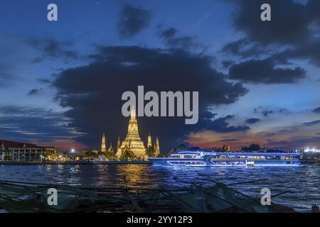 Wat Arun, Tempel der Dämmerung bei Sonnenuntergang mit dunklen Wolken. Boote auf dem Fluss Chao Phraya. Touristenattraktion in Bangkok, Thailand, Asien Stockfoto