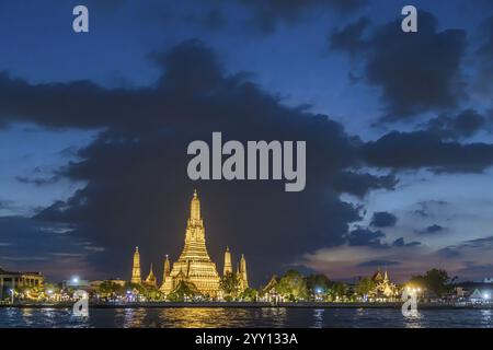 Wat Arun, Tempel der Dämmerung bei Sonnenuntergang mit dunklen Wolken. Boote auf dem Fluss Chao Phraya. Touristenattraktion in Bangkok, Thailand, Asien Stockfoto