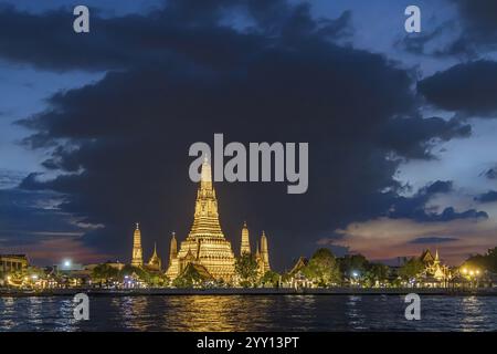 Wat Arun, Tempel der Dämmerung bei Sonnenuntergang mit dunklen Wolken. Boote auf dem Fluss Chao Phraya. Touristenattraktion in Bangkok, Thailand, Asien Stockfoto