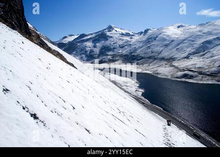 Ein atemberaubender Blick auf die schneebedeckten Berge in Bolivien, mit einem ruhigen See und einer gewundenen Straße. Stockfoto