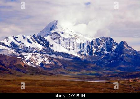 Boliviens majestätischer Berg Huayna Potosí in Bolivien mit seinem schneebedeckten Gipfel, der vor einem dramatisch bewölkten Himmel steht. Stockfoto