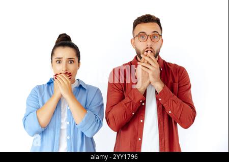 Schockierte Männer und Frauen, die ihren Mund mit Händen bedecken, überrascht oder ungläubig zeigen, in lässiger Kleidung gekleidet, stehen auf isoliertem weißen Hintergrund und schauen in die Kamera Stockfoto