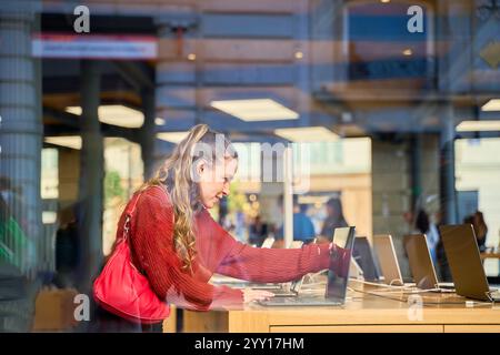 Junge kaukasische Frau, die in einem Elektronikgeschäft auf Laptops surft Stockfoto