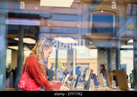 Junge kaukasische Frau, die in einem Elektronikgeschäft auf Laptops surft Stockfoto