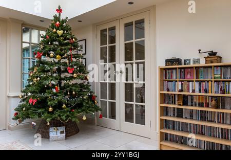 Inneneinrichtung mit geschmücktem Weihnachtsbaum und Geschenk unter dem Baum im Wohnzimmer Wintergarten, Großbritannien Stockfoto