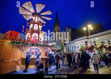 Schwerin, Deutschland. Dezember 2024. Besucher stehen an einem Verkaufsstand mit Glühwein und heißen Getränken auf dem Weihnachtsmarkt vor der Kathedrale. In Mecklenburg-Vorpommern enden die meisten großen Weihnachtsmärkte wenige Tage vor Heiligabend - nur in Schwerin und Stralsund können Sie nach den Feiertagen noch den Glühweinstand und den Mutzenstand besuchen. Der Schweriner Markt endet am 30. Dezember, der Stralsunder Markt endet erst im Dezember 31. Quelle: Jens Büttner/dpa/Alamy Live News Stockfoto