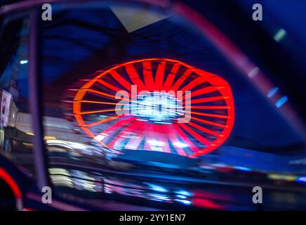 Schwerin, Deutschland. Dezember 2024. Ein Riesenrad vom Weihnachtsmarkt spielt in einer Autoscheibe. In Mecklenburg-Vorpommern enden die meisten großen Weihnachtsmärkte wenige Tage vor Heiligabend - nur in Schwerin und Stralsund können Sie nach den Feiertagen noch den Glühweinstand und den Mutzenstand besuchen. Der Schweriner Markt endet am 30. Dezember, der Stralsunder Markt endet erst im Dezember 31. Quelle: Jens Büttner/dpa/Alamy Live News Stockfoto