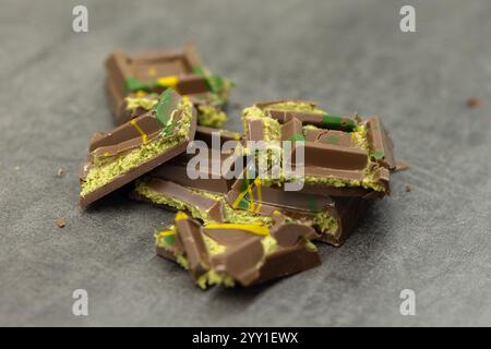 Ein Stück Dubai-Schokolade auf grauem Hintergrund. Grüner Kadayif und Pistazien mit Pistazien im Trenddessert. Nahaufnahme, selektiver Fokus. Hohe Qualität Stockfoto