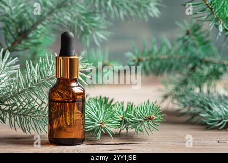 Tropfer für ätherisches Tannenöl. Ätherisches Öl der Kiefer und Fichte in Bernsteinglasflasche und Grüntannenzweigen. Stockfoto