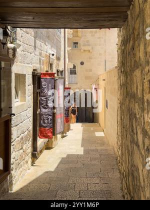 Korcula, Kroatien - 30. Juni 2024: Depolo Alley mit Marco Polo Center und Souvenirshop in der engen Schlucht. Junge Frau, die Treppen klettert. Stockfoto