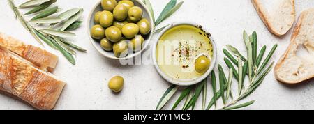 Olivenöl, Oliven und Brot. Bio-Olivenöl in der Schüssel mit grünen Oliven, Blättern und frischem Ciabatta-Brot auf weißem Hintergrund, Banner. Gesunder mediter Stockfoto