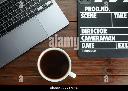 Filmklatscher, Laptop und Kaffee auf Holztisch, flache Ladefläche Stockfoto