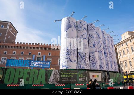 Blick auf Autos, die neben „Konstellationen von Rom“ vorbeifahren, dem Titel der monumentalen Intervention, die Pietro Ruffo auf den zehn Silos unterzeichnet hat, die die Baustelle der Metro C auf der Piazza Venezia begrenzen. Das erste Werk eines Zyklus wurde vorgestellt, der sich in den kommenden Monaten auf dieser neuen Oberfläche abwechseln wird, die der zeitgenössischen Kunst verliehen wird. Mit „Murales“, dem Titel des Projekts, das von Webuild, einem Unternehmen, das am Bau der C-Linie der U-Bahn in Rom arbeitet, gefördert wurde, verwandelt sich die Baustelle in eine Gelegenheit zur Stadterneuerung. Stockfoto