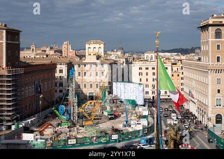Rom, Italien. Dezember 2024. Kräne und LKWs rund um die „Konstellationen von Rom“, den Titel der monumentalen Intervention, die Pietro Ruffo auf den zehn Silos unterzeichnet hat, die die Baustelle der Metro C auf der Piazza Venezia begrenzen. Das erste Werk eines Zyklus wurde vorgestellt, der sich in den kommenden Monaten auf dieser neuen Oberfläche abwechseln wird, die der zeitgenössischen Kunst verliehen wird. Mit „Murales“, dem Titel des Projekts, das von Webuild, einem Unternehmen, das am Bau der C-Linie der U-Bahn in Rom arbeitet, gefördert wurde, verwandelt sich die Baustelle in eine Gelegenheit zur Stadterneuerung. (Bild: © Stefano Co Stockfoto