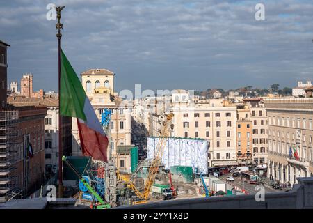 Rom, Italien. Dezember 2024. Kräne und LKWs rund um die „Konstellationen von Rom“, den Titel der monumentalen Intervention, die Pietro Ruffo auf den zehn Silos unterzeichnet hat, die die Baustelle der Metro C auf der Piazza Venezia begrenzen. Das erste Werk eines Zyklus wurde vorgestellt, der sich in den kommenden Monaten auf dieser neuen Oberfläche abwechseln wird, die der zeitgenössischen Kunst verliehen wird. Mit „Murales“, dem Titel des Projekts, das von Webuild, einem Unternehmen, das am Bau der C-Linie der U-Bahn in Rom arbeitet, gefördert wurde, verwandelt sich die Baustelle in eine Gelegenheit zur Stadterneuerung. (Bild: © Stefano Co Stockfoto