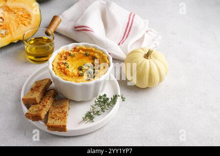 Hausgemachter Kürbiskichererbsenhummus in einer weißen Schüssel auf hellem Hintergrund. Stockfoto