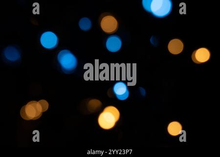 Blaue und orangene Bokeh-Lichter auf schwarzem Hintergrund, weihnachtskonzept, moderner abstrakter Hintergrund Stockfoto