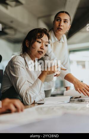 Zwei verschiedene Geschäftsfrauen nehmen an einem Brainstorming Teil, analysieren Dokumente und diskutieren Ideen für ein neues Projekt. Stockfoto