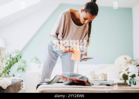 Die junge Studentin organisiert ihre Lernmaterialien in einem gemütlichen Zimmer Stockfoto