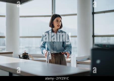 Selbstbewusste Geschäftsfrau, die in einer modernen Büroumgebung präsentiert Stockfoto