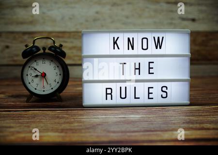 MACHEN SIE SICH MIT DEN REGELN VERTRAUT, die auf der LED Lightbox auf hölzernem Hintergrund, dem Hintergrund des Geschäfts- und Kommunikationskonzepts Stockfoto