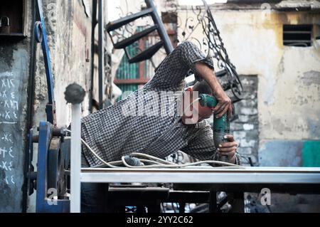 Ein gelernter Handwerker in Alexandria, Ägypten, konzentrierte sich auf das präzise Schweißen von Metall. Eine düstere, authentische Darstellung traditioneller Handwerkskunst. Stockfoto